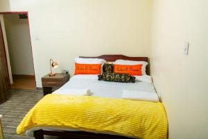 a bed with orange pillows and a yellow blanket at Micasa Pent House MAIN in Limuru