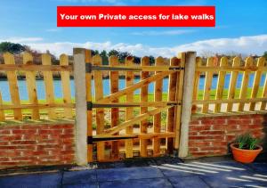 uma cerca de madeira em frente a uma parede de tijolos em Romantic Lakeside Cottage by the Beach! Relax by the Cosy Log Burner & fall asleep to the sound of Waves - The Perfect Romantic Great Escape by the Sea! - You Won't want to Leave! and It's Pet Friendly too ! em Mablethorpe