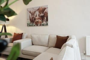 a living room with a couch and a painting of bulls at Spacious 3BR Flat in Cowbridge Centre in Cowbridge