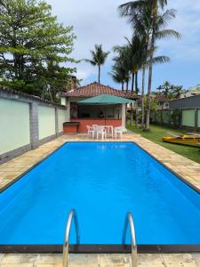 a large blue swimming pool in front of a house at Farol dos Coqueiros in Angra dos Reis +39 photos