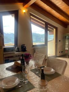 mesa de comedor con sillas y 2 ventanas en Ronco Frati, piscina vista lago, en Pisogne