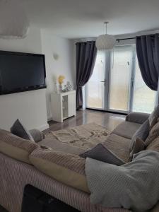een woonkamer met een bank en een flatscreen-tv bij Comfy Home in Kirkby