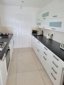 een keuken met witte kasten en een zwart aanrechtblad bij Comfy Home in Kirkby