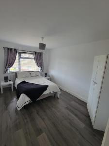 een witte slaapkamer met een bed en een groot raam bij Comfy Home in Kirkby