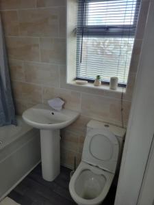 een badkamer met toilet, wastafel en raam bij Comfy Home in Kirkby