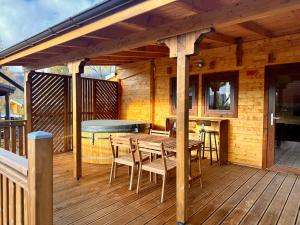 a wooden deck with a table and chairs on it at Le Chalet de la Vernie in Saint-Léger-les-Mélèzes
