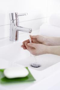 a person holding a glass under a bathroom faucet at SleepySleepy Hotel Fulda in Fulda +14 photos