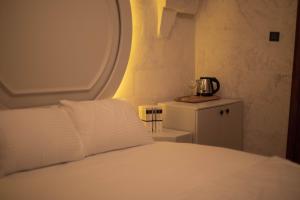 a bedroom with a white bed and a small table at Hotel Estara in Urfa