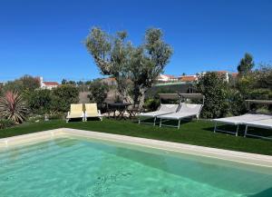 a swimming pool with two chairs and a table at L'Escale au Portugal Villa-B&B-Spa in Ataíja de Baixo