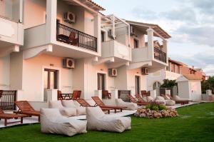 duży budynek apartamentowy z krzesłami i trawnikiem w obiekcie Hyacinthus-Cressida Seaside Apartments w Acharavi