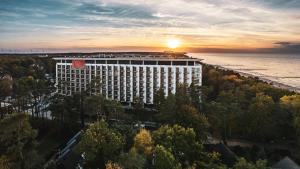 a tall white building with a sunset in the background at Premium Apartament PINEA Pobierowo in Pobierowo
