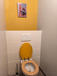 La salle de bains est pourvue de toilettes et d'un couvercle jaune. dans l'établissement Chez celine, à Villieu
