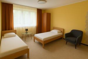 a room with two beds and a chair and a window at BIZAR Hostel in Sadowa