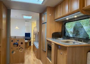 a small kitchen with a sink and a bedroom at Aurora Caravan Near Bergen - NO shower in Strusshamn