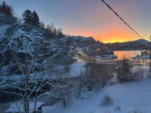 a snow covered hill with a road and a sunset at Aurora Caravan Near Bergen - NO shower in Strusshamn