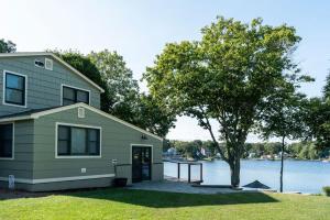 ein Haus mit einem Baum neben einem Wasserkörper in der Unterkunft The Lake House in Uncasville