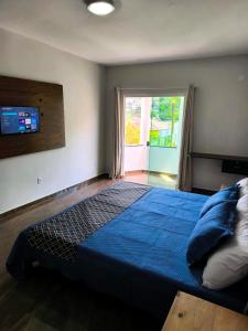 a bedroom with a large blue bed with a window at Farol dos Coqueiros in Angra dos Reis