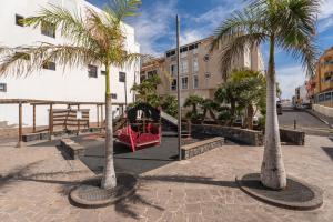 a playground with palm trees and a red train at Two bedroom apartment with sea view in Los Abrigos in Los Abrigos