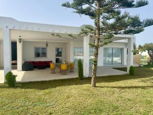 een huis met een dennenboom in de tuin bij Complexe Touristique Sidi Salem in Bizerte