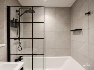 a bathroom with a shower and a tub and a sink at Pappilo at The Heim Residences in Manchester +22 photos