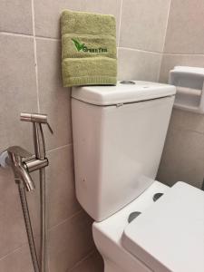 a bathroom with a toilet with a green towel on top at Comfy Hut-KLIA SEPANG in Sepang +7 photos