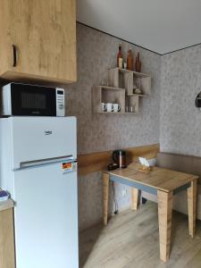 a kitchen with a white refrigerator and a wooden table at Апартаменты у новому будинку біля Либідь Плази-Ощадбанк in Khmelʼnytsʼkyy