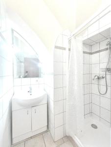 Un baño blanco con lavabo y ducha en City Rooms Steyr, en Steyr