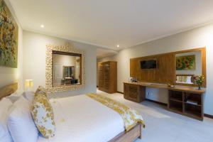 a bedroom with a large bed and a mirror at Alamdini Resort Ubud in Ubud