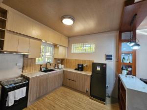 a kitchen with wooden cabinets and a black refrigerator at Gloria Beach House - Baler in Baler