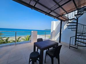 a table and chairs on a balcony with the ocean at Gloria Beach House - Baler in Baler
