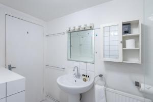 a white bathroom with a sink and a mirror at Charming 1BD Flat with Garden Wimbledon Village in London