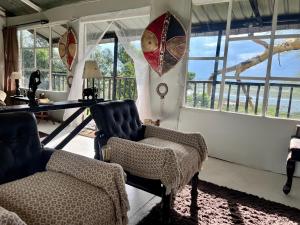 a living room with two chairs and a table and windows at TREE HOUSE Lodge in Gilgil