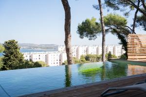 a swimming pool with trees and buildings in the background at Villa vu mer et étang de thau in Sète