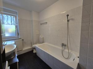 a bathroom with a tub and a toilet and a sink at Mikra Homes24 in Meerane in Meerane