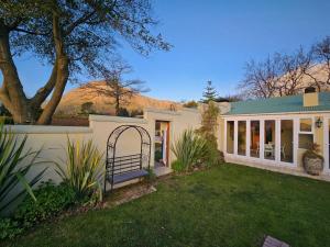 une maison avec un jardin et une montagne en arrière-plan dans l'établissement Franschhoek Farm Cottages, à Swiss Farm