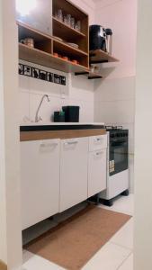 a white kitchen with a sink and a stove at Aconchego da day in Aracaju