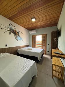 a bedroom with two beds and a fish painting on the wall at Suítes da Sereia in Cananéia