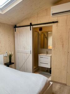 a bedroom with a bed and a bathroom with a sink at Tiny House The Wave in Ons Belang