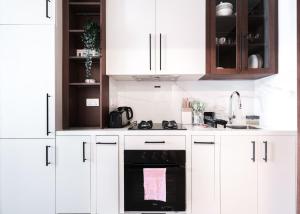 a white kitchen with white cabinets and an oven at StayShort - Town Square sleeps 2 in Great Location in ‘Ūd al Bayḑāʼ