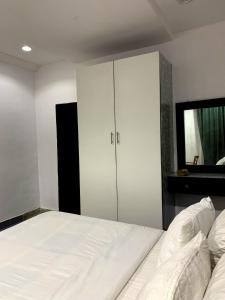 a bedroom with a large white bed and a cabinet at Citadel Royal apartment in Lekki