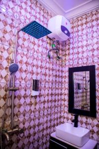 a bathroom with a pink tiled wall with a mirror at Citadel Royal apartment in Lekki