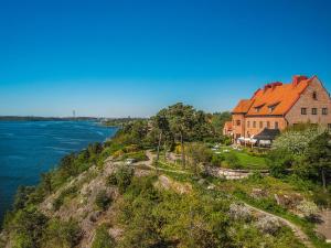 una imagen de una casa en un acantilado junto al agua en Högberga Gård, en Lidingö