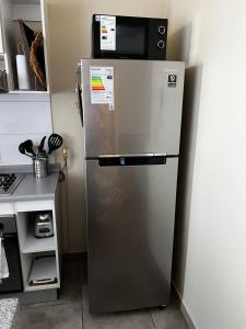 Un refrigerador con un microondas encima. en comfortable, pleasant and centrally located on the 1st floor, en Linares