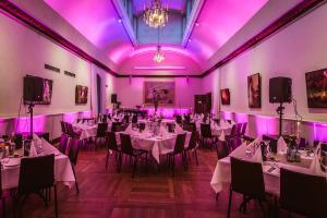 a room filled with tables and chairs with purple lighting at Högberga Gård in Lidingö
