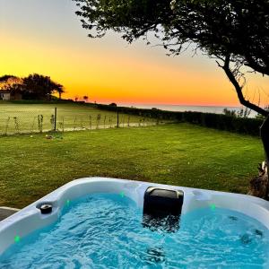 a bath tub sitting in a field with a tree at Sea Marge Seaview Lodges in Overstrand