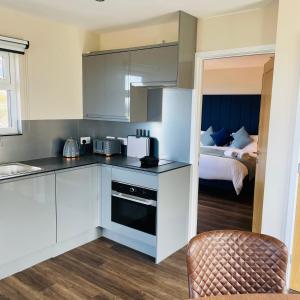 a kitchen with white cabinets and a bed in a room at Sea Marge Seaview Lodges in Overstrand