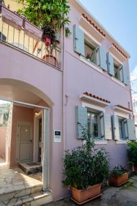 een roze gebouw met planten ervoor bij Dora Studios by PaxosRetreats in Gaios