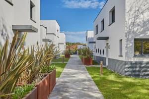 une passerelle entre deux bâtiments blancs avec des plantes dans l'établissement Villas Odalys Le Domaine d Anadara, à Anglet