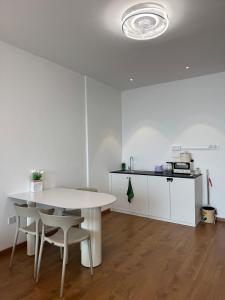 a white table and chairs in a room with a kitchen at The Calm Corner Summermall in Kota Samarahan