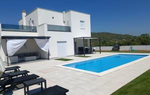 a villa with a swimming pool in front of a house at Holiday home Iva by Villas Guide in Vrulje